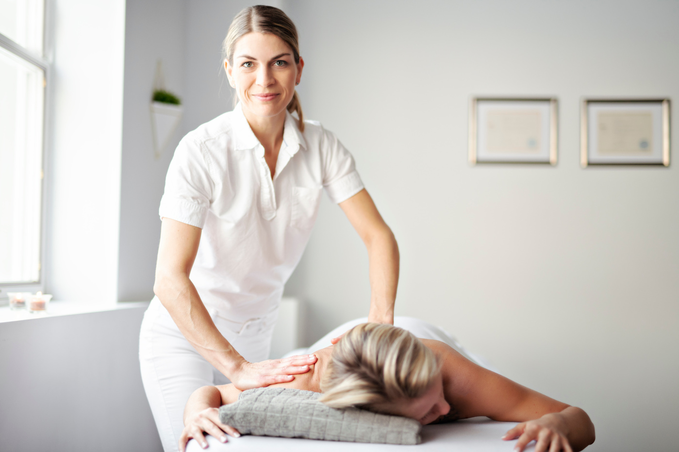A medical masseuse with a federal certificate massages a patient's tense areas to relieve the pain.