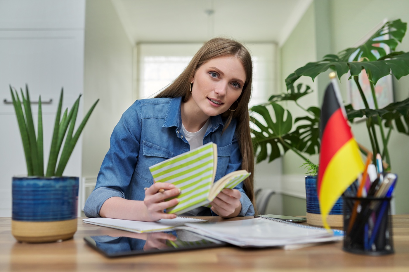 Eine Schülerin sitzt am Pult und ist am Deutsch lernen.