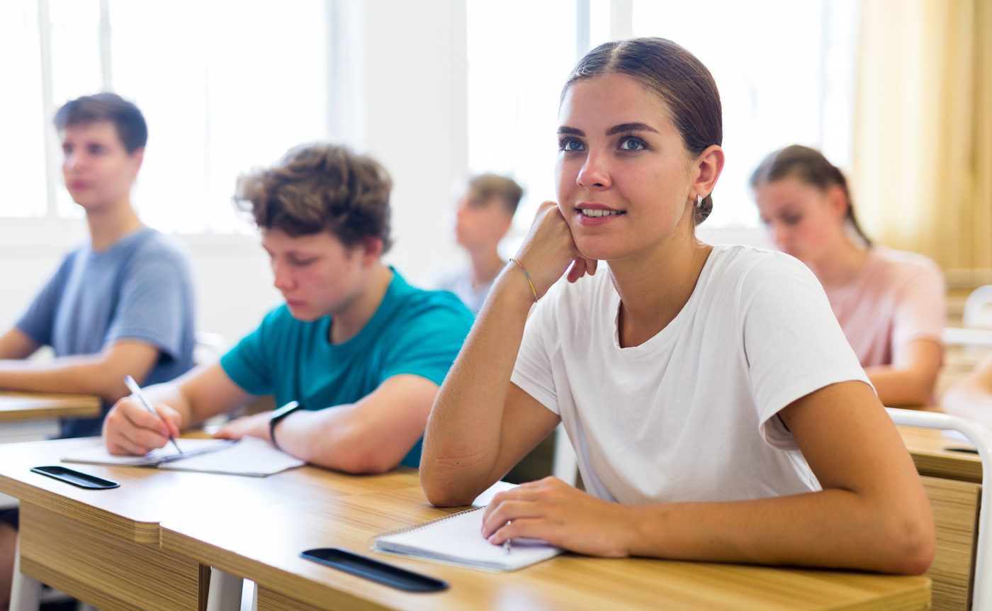 Eine Schülerin sitzt in einem Italienischkurs und hört der Lehrerin gespannt zu.