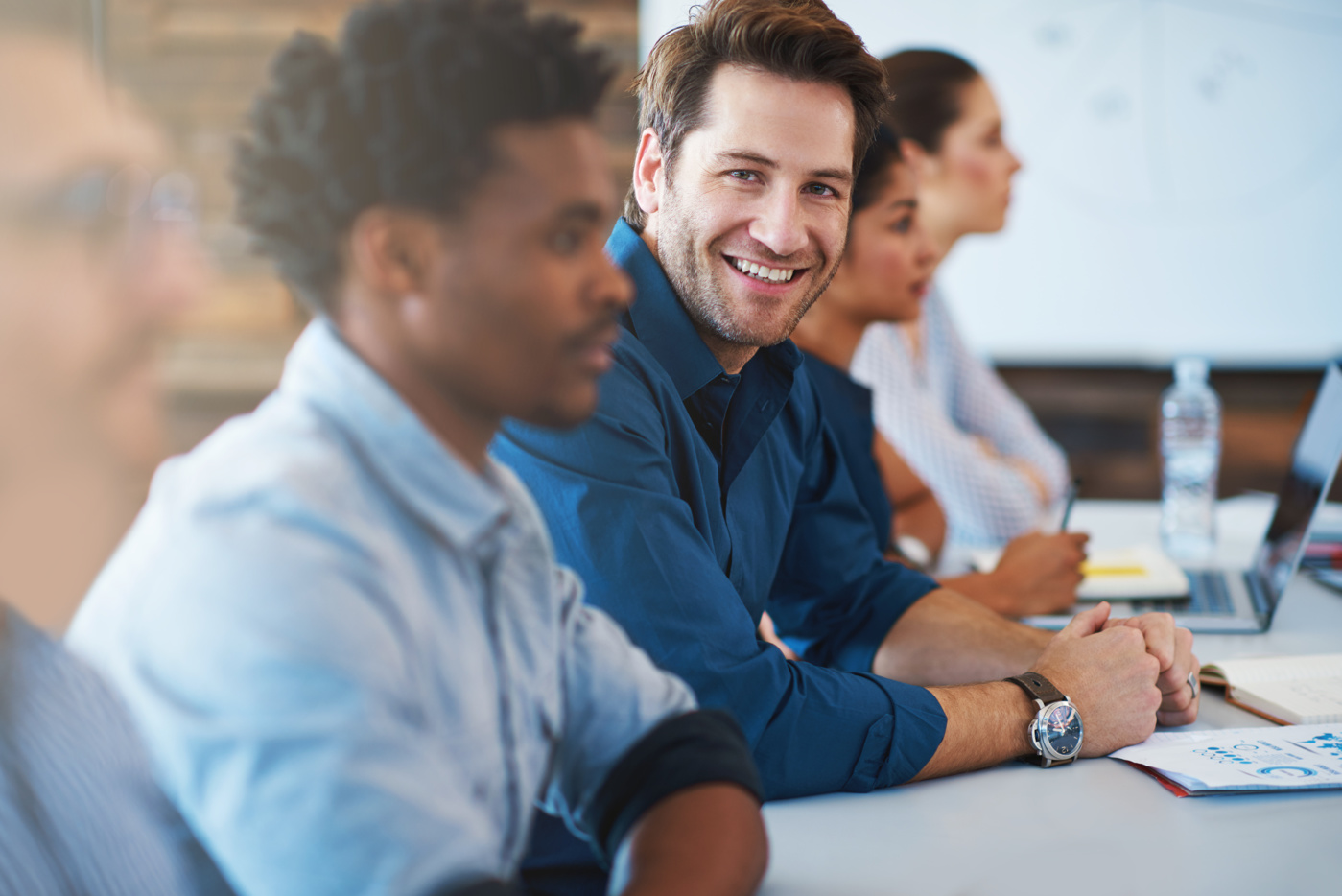 A graduate of a Business Administration program at a university of applied sciences is sitting in a management meeting with other colleagues.