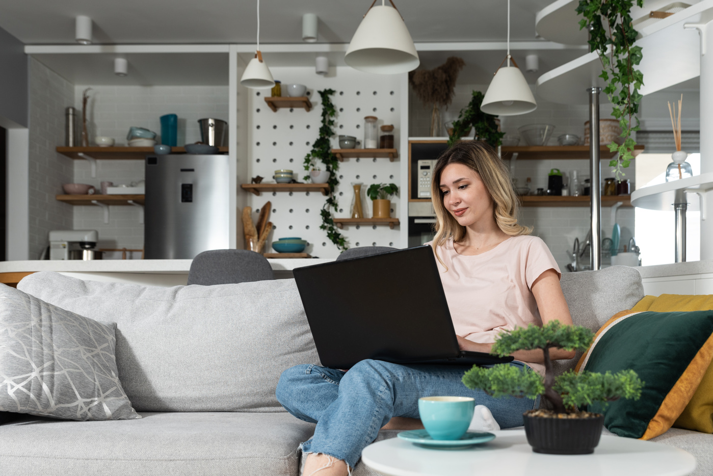 Une femme est assise sur le canapé et cherche des meubles feng shui sur Internet.