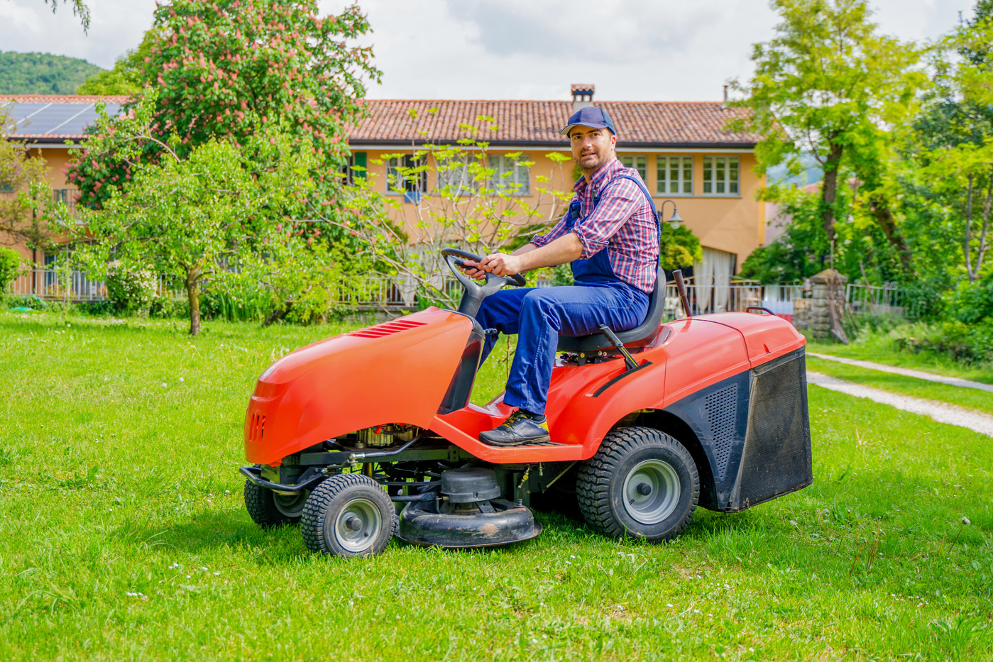 Janitor with Federal Diploma of Higher Education mows the lawn.