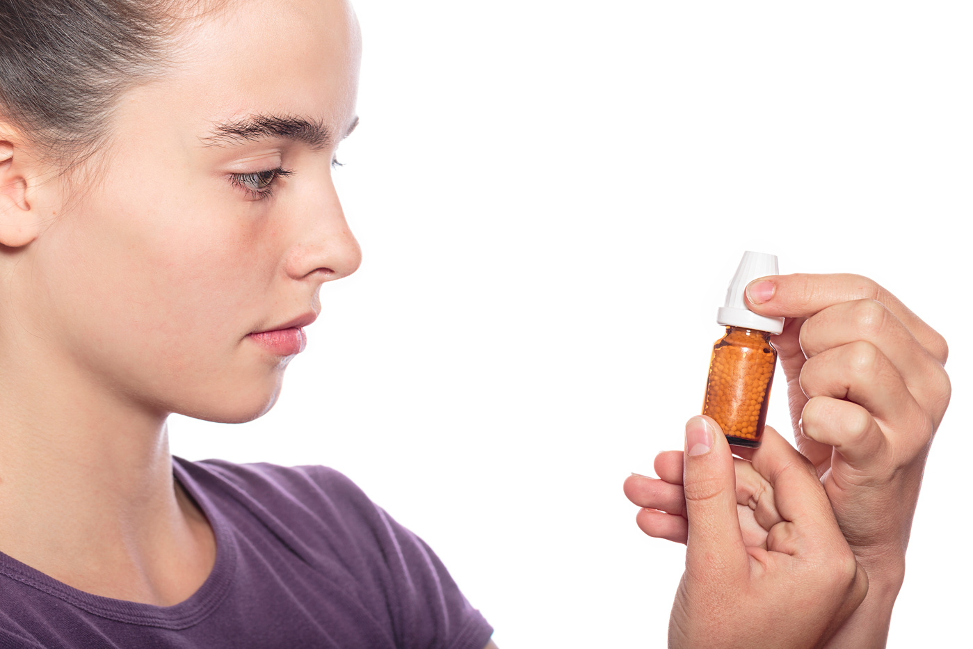 A woman holds a bottle of globules in her hands.