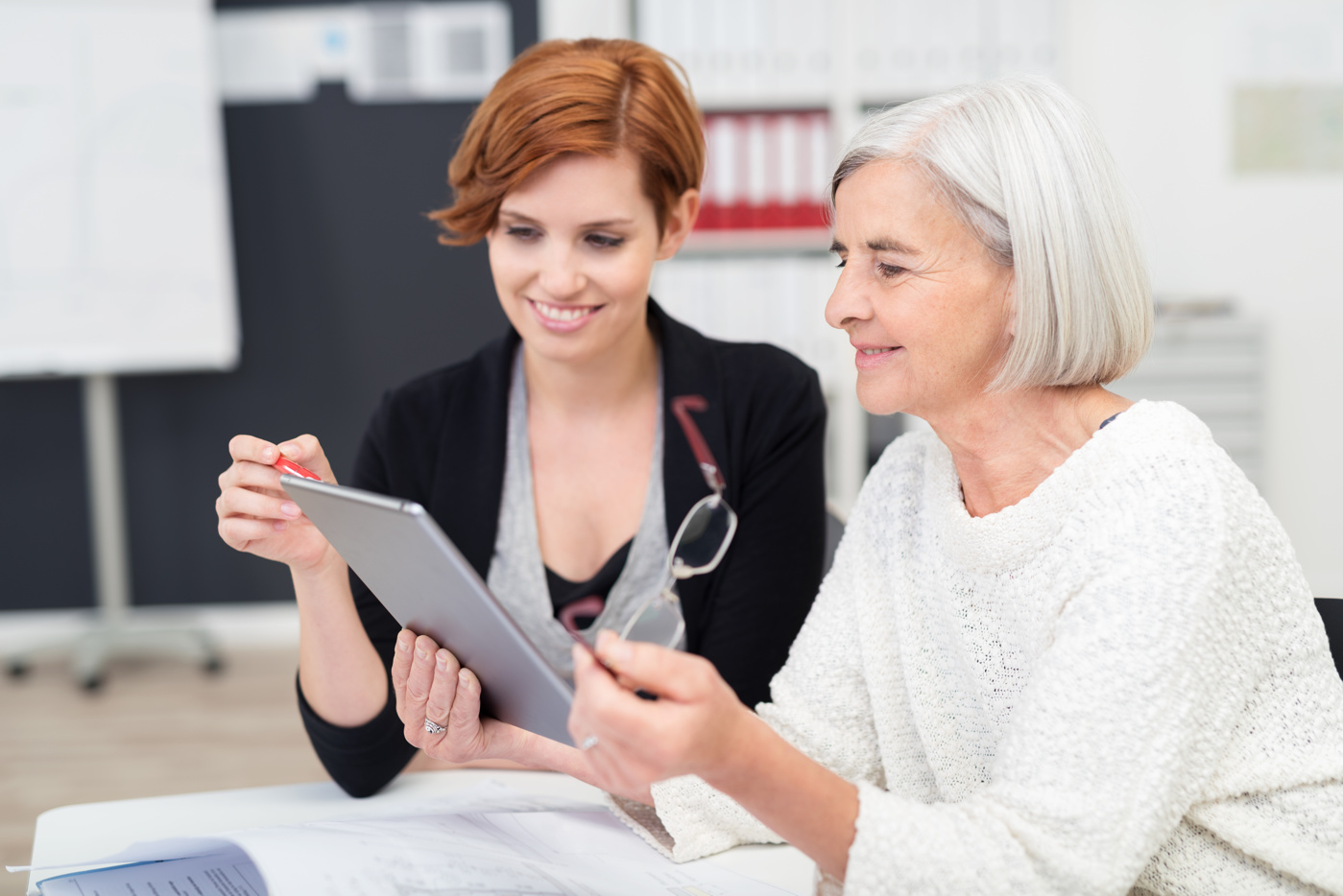Une accompagnatrice sociale aide une femme âgée à trouver une activité de loisirs appropriée sur sa tablette.