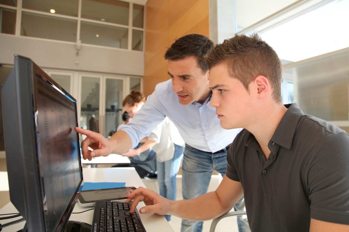 Ein Lehrer instruiert einen Schüler am PC innerhalb eines ECDL-Kurses
