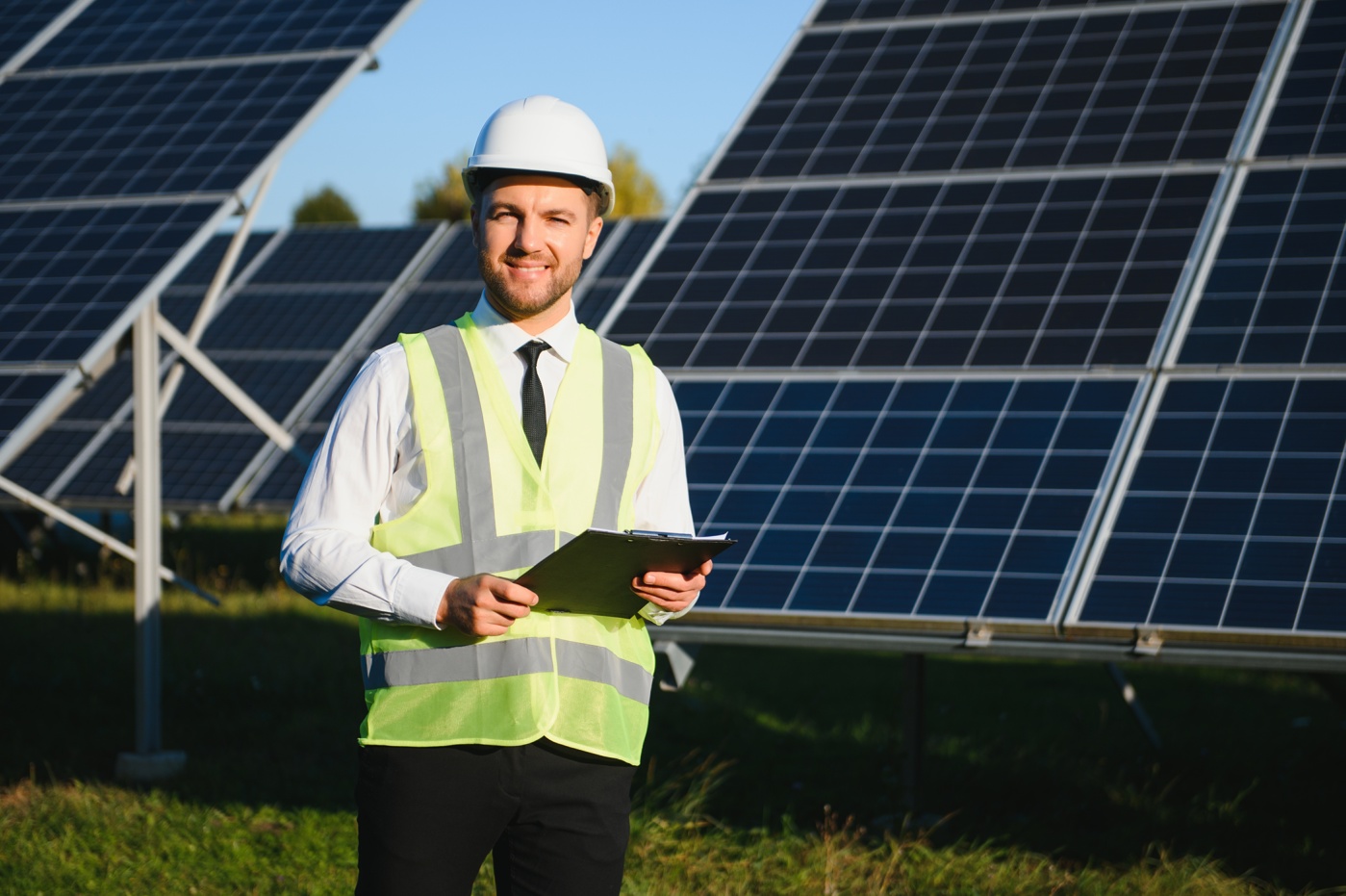 Umwelttechniker steht mit Notepad vor einem Solarpark und analysiert die Anlage nach Ausbildung Energie- und Umwelttechnik HF