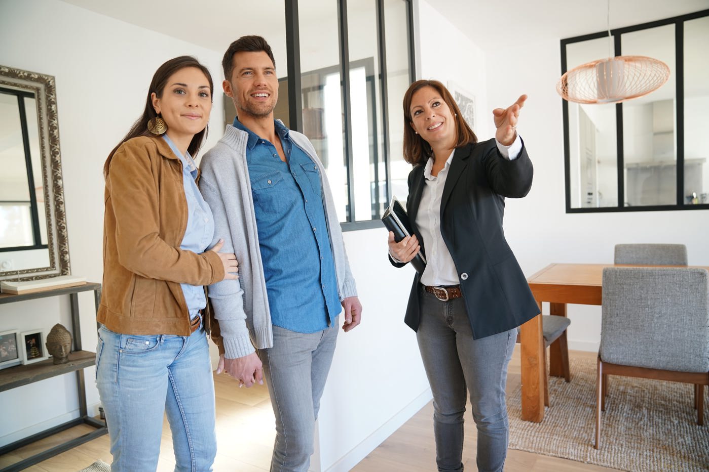 Immobilienvermarkterin zeigt einem interessierten Paar das Haus.