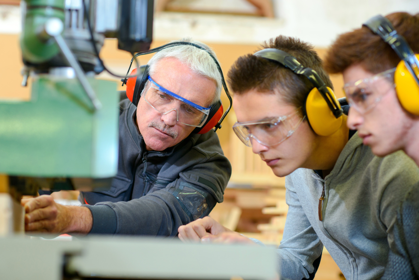 Un formatore pratico istruisce due apprendisti su una macchina