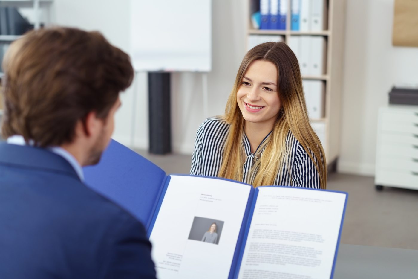 Un responsable des ressources humaines examine le dossier de candidature d'une candidate.