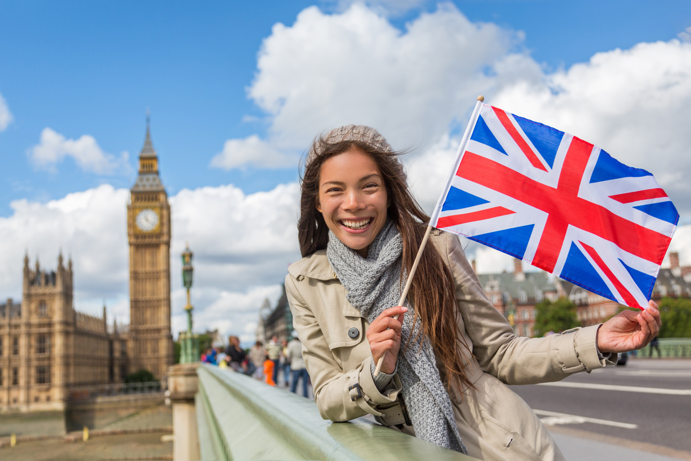 Eine Frau, die einen Englisch Sprachaufenthalt in England macht, hält die englische Flagge in der Hand und lacht in die Kamera.